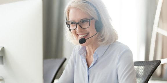 Frau in Videokonferenz Eine Frau sitzt vor ihrem Laptop und trägt ein Headset.
