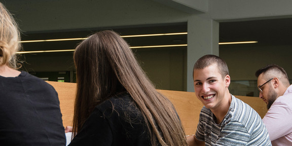 Rear view of five students. One of them is smiling at the camera.